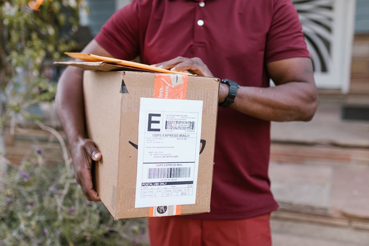 gallery-4 Close-up of a courier delivering a parcel with USPS express mail label outdoors.