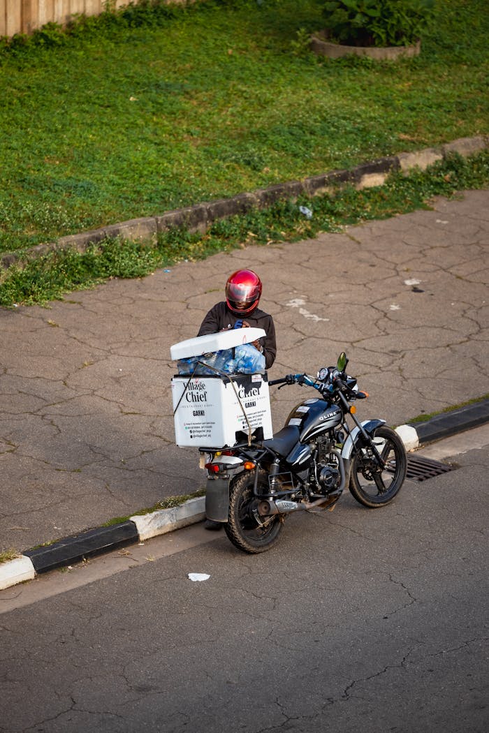 our-experience Motorcycle delivery driver on a city street in Abuja, Nigeria.